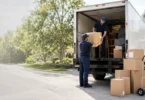 Professional long distance movers loading household boxes into a moving truck